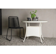 Trädgårdsscen med en svart stol och ett vitt trädgårdsbord med glasskiva