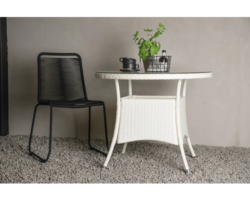 Trädgårdsscen med en svart stol och ett vitt trädgårdsbord med glasskiva