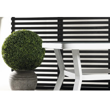 Dekorativ grön konstgjord växt i kruka bredvid ett vitt bord