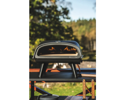 Vedeldad pizzaugn på ett bord utomhus.