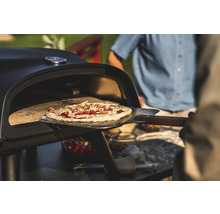 Pizza tillagas med en pizzaspade i en pizzaugn.