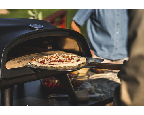 Pizza tillagas med en pizzaspade i en pizzaugn.