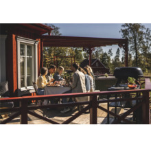 En grupp människor njuter av en utomhusmåltid på en träterrass med en grill.