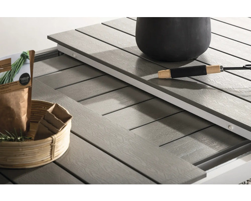 Detaljvy av ett trädgårdsbord med utdragbar design, blomkruka, trädgårdssax och dekoration