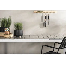 Uteplats med örter i krukor, trädgårdsredskap och ett bord med stol.