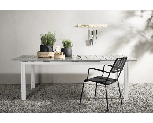 Trädgårdsscen med matbord, stol och trädgårdsredskap på en vägg