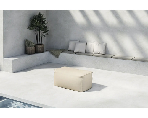 Ljus uteplats med sittbänk, kuddar, sidobord och växter