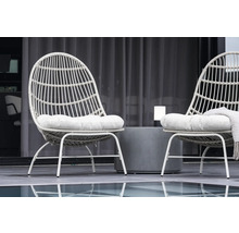 Två rottingfåtöljer med sittdynor och ett bord utomhus.