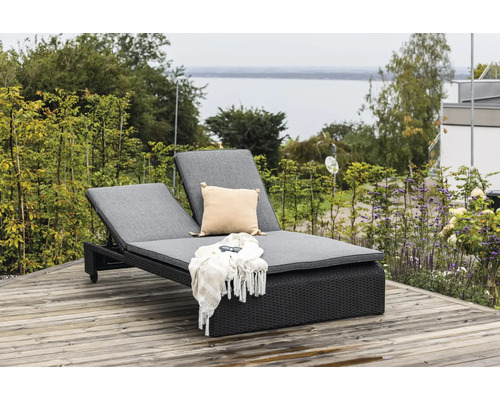 Dubbel solstol av polyrotting med grå dynor, kudde, filt och solglasögon på en träaltan