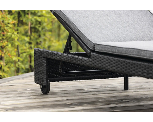 Detaljvy av en trädgårdsliggstol i rotting med hjul.