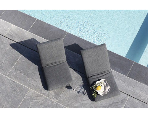 Två grå solstolar bredvid en pool på stenplattor.