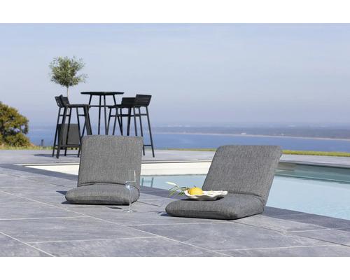 Scen med två grå loungestolar, ett bord och stolar i bakgrunden bredvid en pool
