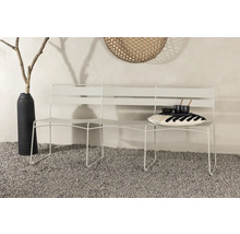 Vit trädgårdsbänk med kudde och porslin på grusgolv