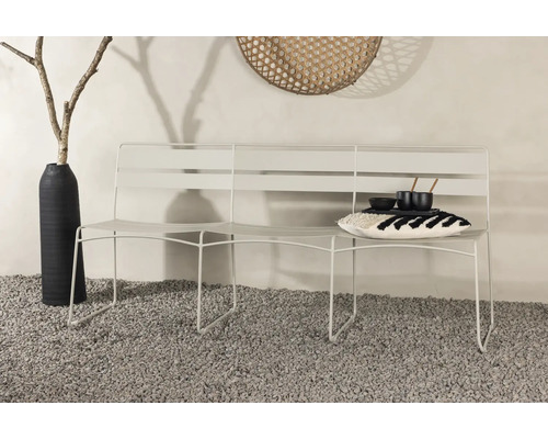 Vit trädgårdsbänk med kudde och porslin på grusgolv