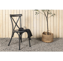 Dekorativ scen med en stol, en drickmugg, en trasa och en växt i en jutekorg framför en trävägg.