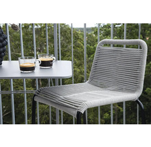 Balkongscen med ett bord, två koppar kaffe och en flätad stol.