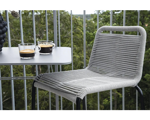 Balkongscen med ett bord, två koppar kaffe och en flätad stol.