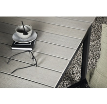 Närbild av ett trädgårdsbord med bok, kopp, glasögon och kudde