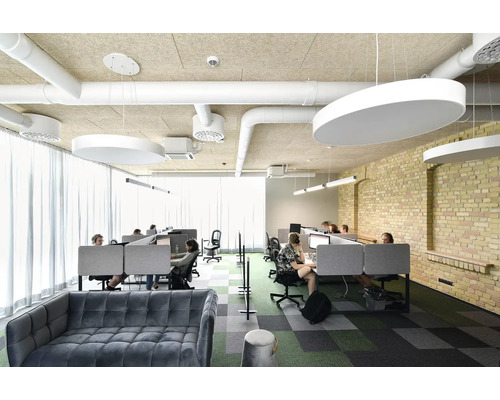 Kontorsutrymme med skrivbord, taklampor och sittplatser för anställda.