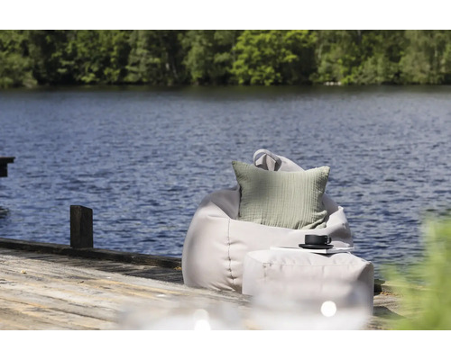 Scen med sittsäck, kudde och pall vid sjön