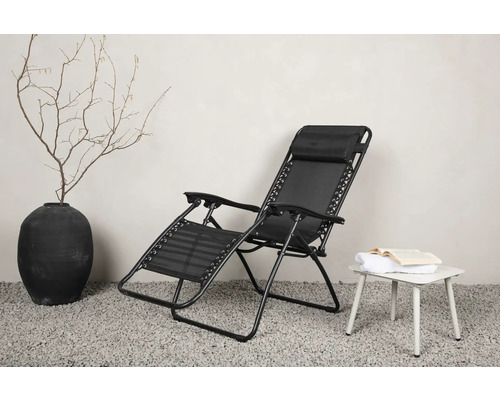 Svart relaxstol i metall med textilklädsel bredvid ett sidobord med en bok