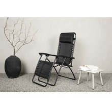 Svart relaxstol av metall och textil bredvid ett sidobord med bok