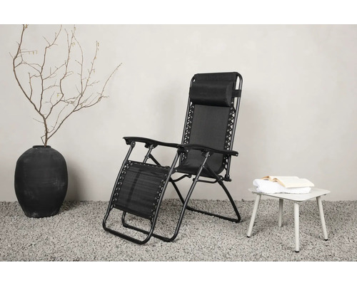 Svart relaxstol av metall och textil bredvid ett sidobord med bok