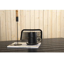 Dekorativ scen med ljusstake, koppar och tidning på ett bord