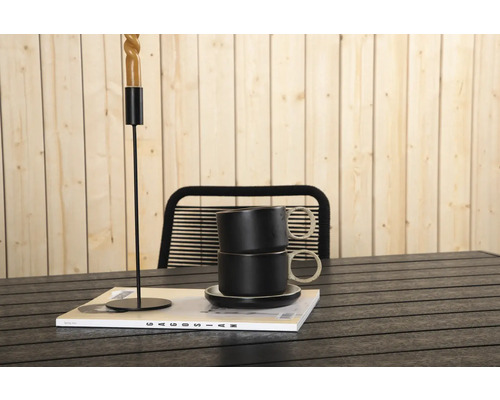 Dekorativ scen med ljusstake, koppar och tidning på ett bord