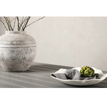 Dekorativ scen med vas, grenar och skål med servett och kronärtskocka