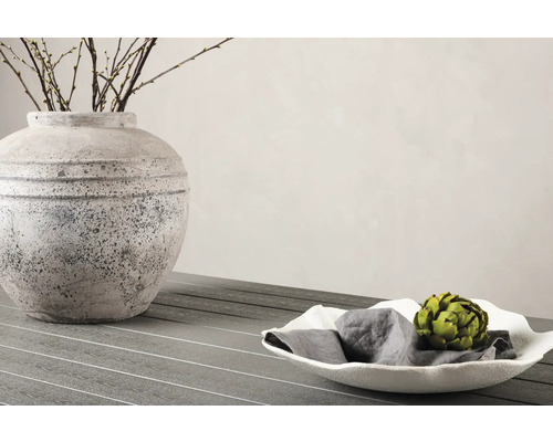 Dekorativ scen med vas, grenar och skål med servett och kronärtskocka