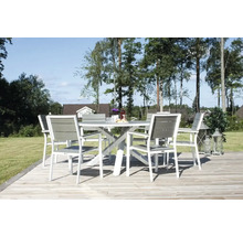 Trädgårdsscen med matgrupp bestående av bord och stolar på en träterrass utomhus.