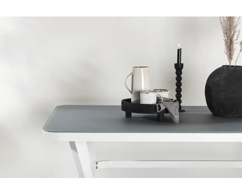 Dekorativ bordsdekoration med karaff, koppar, ljusstake och vas på ett bord