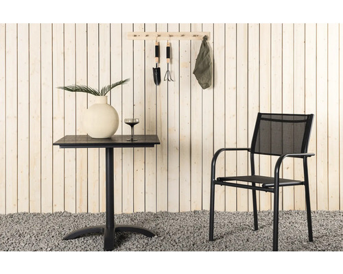 Scen med trädgårdsbord, stol och trädgårdsredskap på väggen