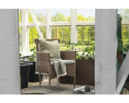 Trädgårdsstol med kudde och filt i ett växthus