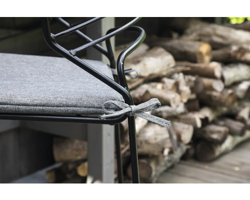 Detalj av en stol med grå sittdyna och dekorativt band