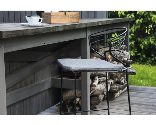 Barstol i metall med grå sittdyna framför en trävägg