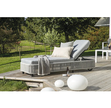 Trädgårdsscen med grå solstol med kuddar och filt på en träterrass