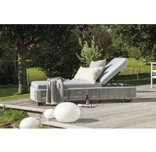 Vadderad trädgårdsstol med kuddar, filt, dryck och tidning utomhus