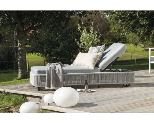 Vadderad trädgårdsstol med kuddar, filt, dryck och tidning utomhus