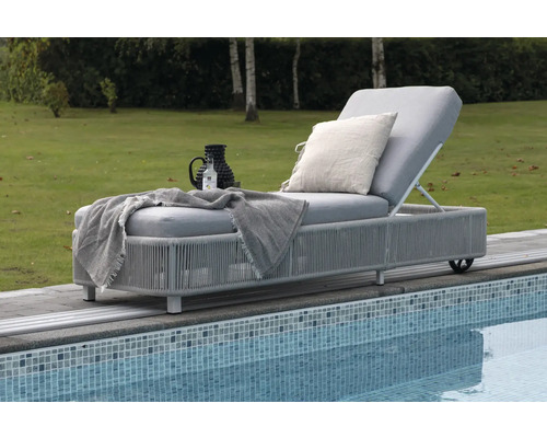 Trädgårdssäng med dyna, kudde och drycker vid poolen