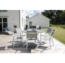 Scen med trädgårdsbord och stolar på en träterrass framför ett hus