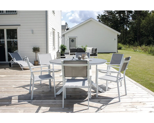 Scen med trädgårdsbord och stolar på en träterrass framför ett hus