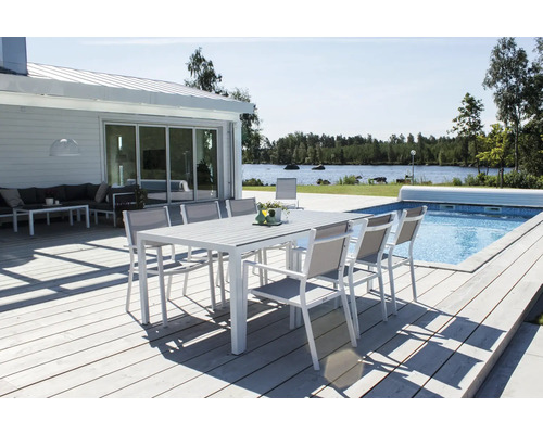 Trädgårdsscen med matbord och stolar på en träterrass bredvid en pool