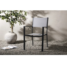 Trädgårdsscen med karmstol, krukväxt och öppen bok på grus