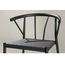 Detaljbild av en svart stol med flätad sits