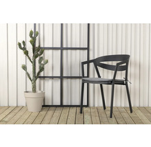 Scen med en stol med armstöd, en kaktus i kruka och ett dekorativt element framför en vägg