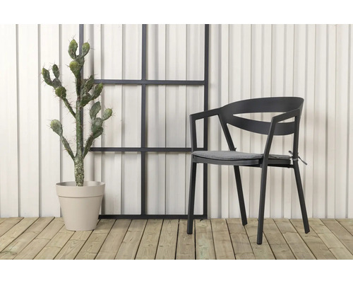 Scen med en stol med armstöd, en kaktus i kruka och ett dekorativt element framför en vägg