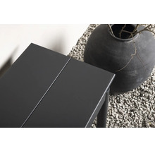 Detalj av ett trädgårdsbord i metall bredvid en stor vas på grus