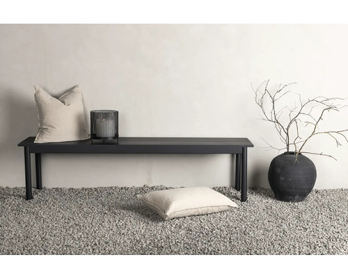 Dekorativ scen med bänk, kuddar, lykta och planteringskärl på grus